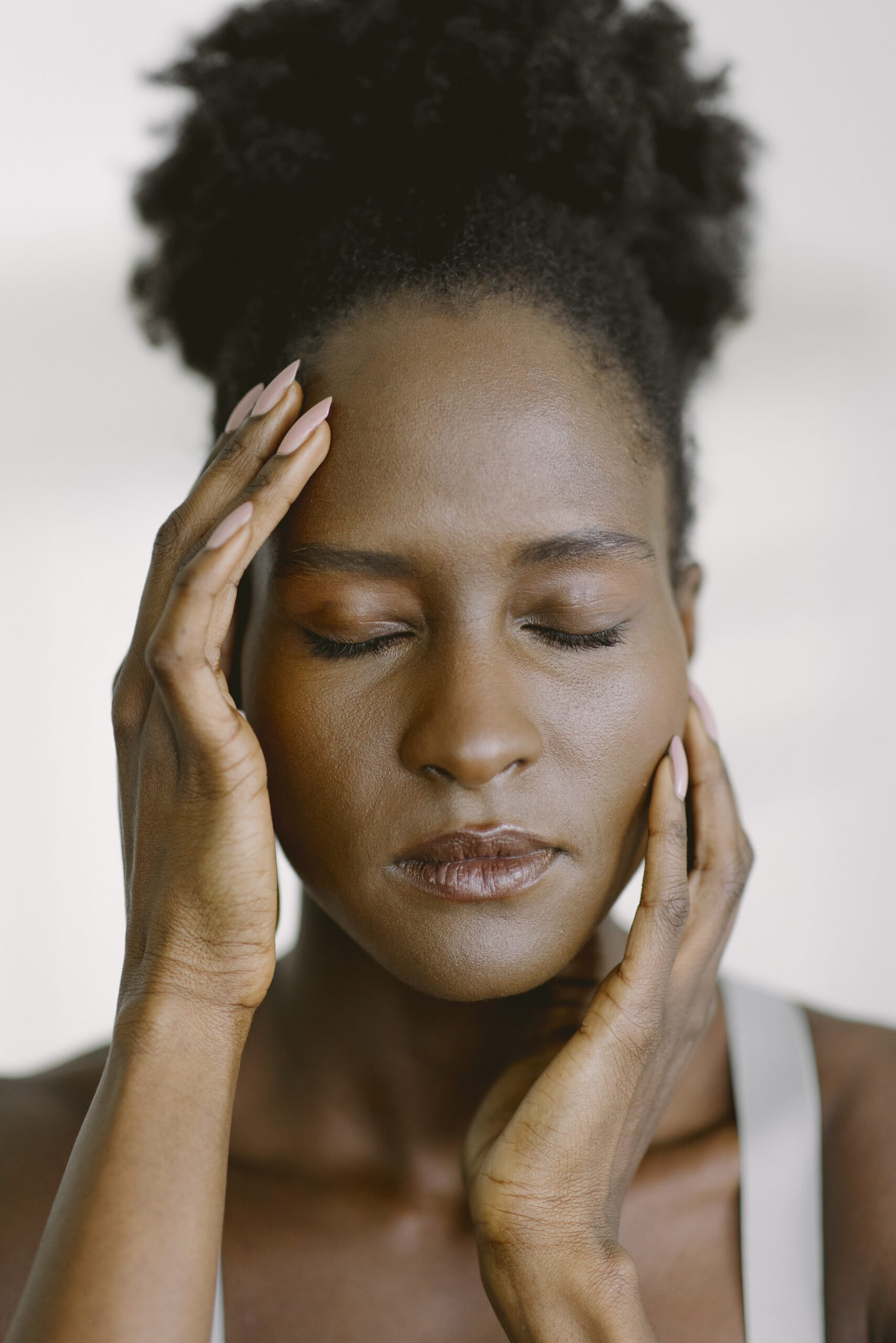 Frau fasst sich fokussiert, vorsichtig ins Gesicht